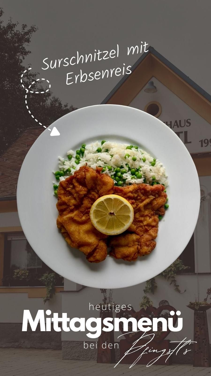 Ein Teller mit gebratenem Kalbfleisch, einer Zitronenscheibe, Reis und Erbsen vor einem Haus.