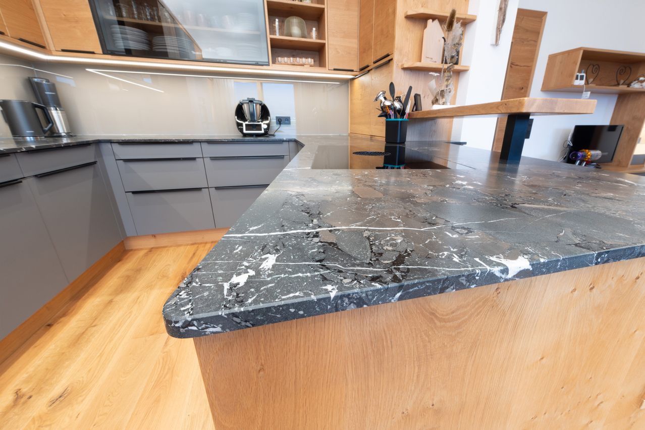 Küchenarbeitsplatte Naturstein Infinity Brown Nahaufnahme mit Küche im Hintergrund.