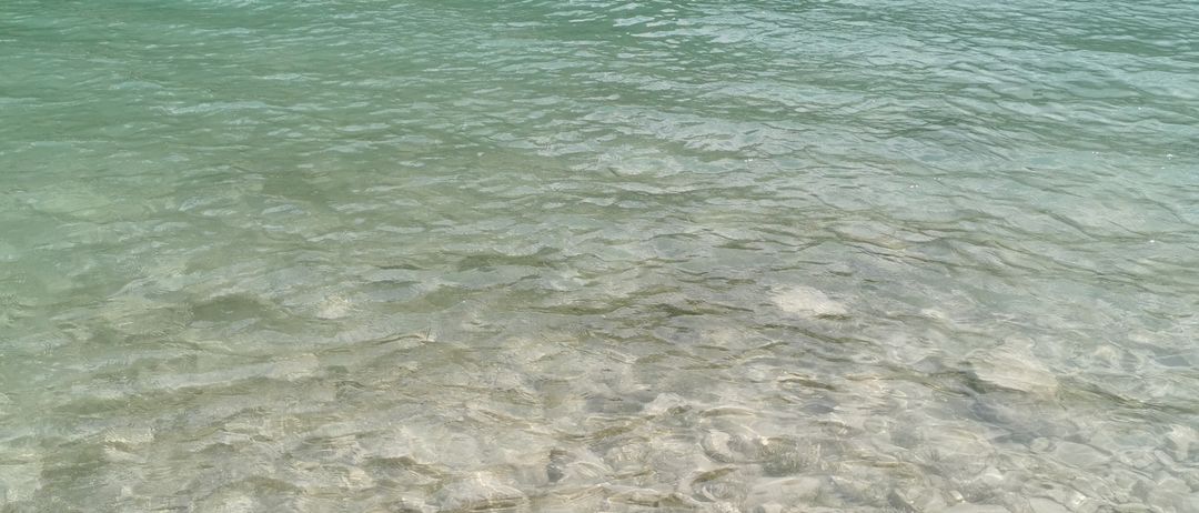 Ein klarer Blick auf einen See mit Felsen am Boden und Menschen am Ufer.