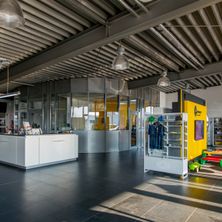 Bild enthält, Indoors, Car, Car Dealership, Building, Interior Design, Wheel, Floor, Chair, Furniture, Person