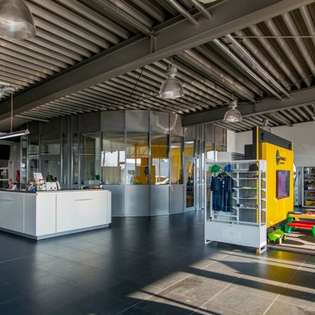 Bild enthält, Indoors, Car, Car Dealership, Building, Interior Design, Wheel, Floor, Chair, Furniture, Person