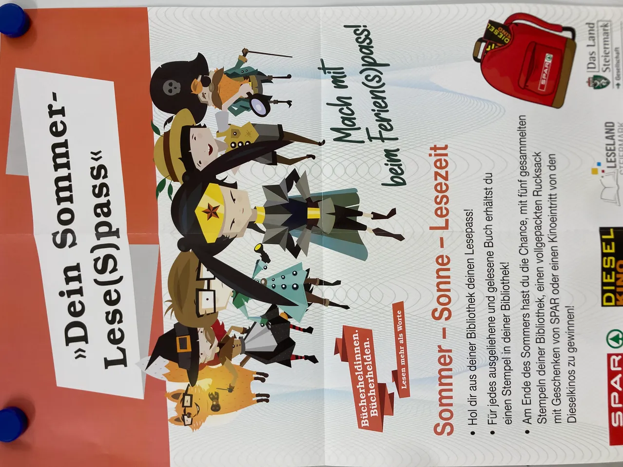 Ein Werbeplakat für einen Lesepass mit einer Gruppe von Comic-Figuren in verschiedenen Kostümen. Der Text enthält einen orangefarbenen Banner mit dem Wort 'Lese(s)pass'. Die Werbung ist auf Deutsch und lädt die Leser zu einem Buchabenteuer ein.