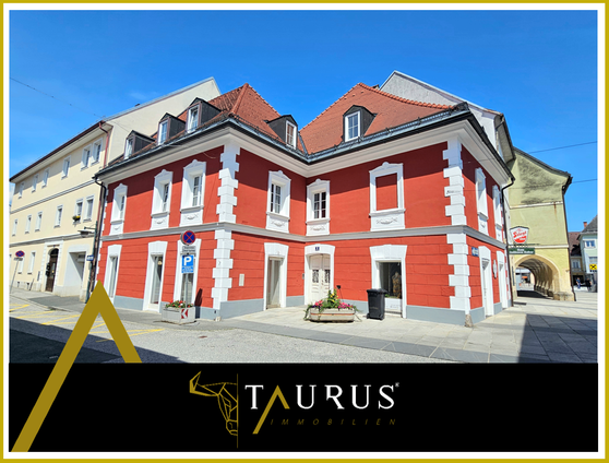 Ein rotes und weißes Gebäude mit einem roten Dach und weißen Verzierungen steht an einer Straße mit einem Parkplatzschild.