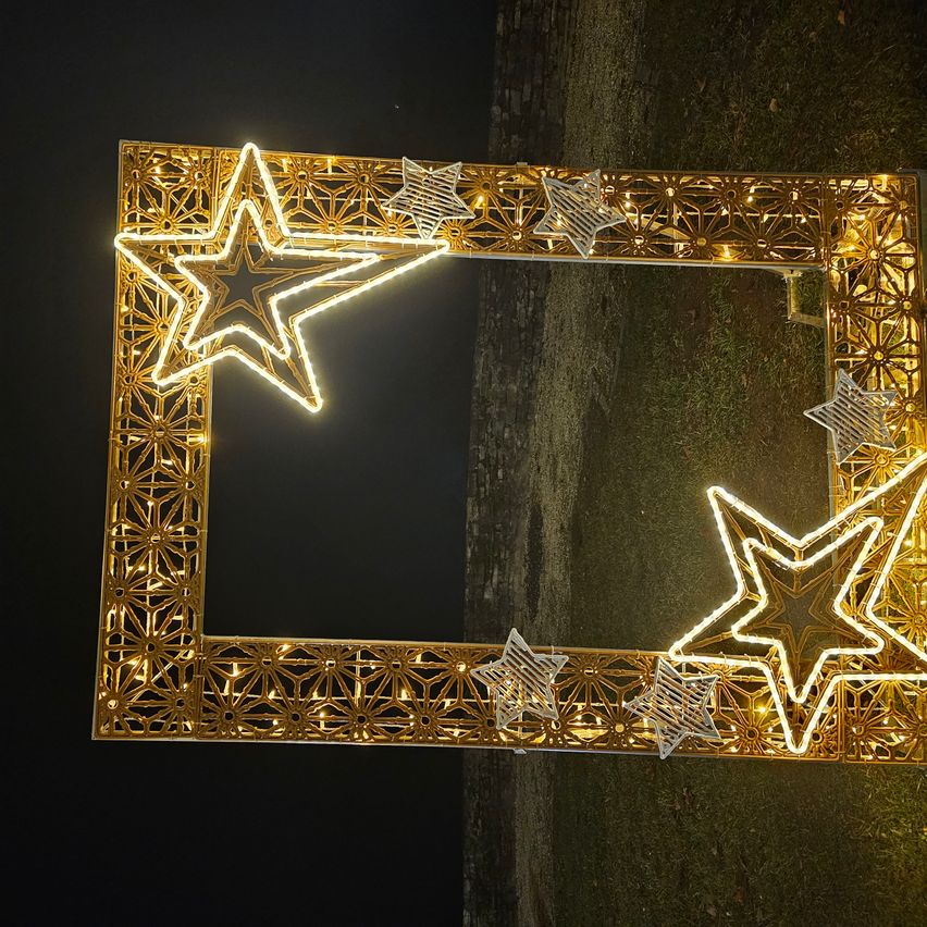 Ein dekorativer Rahmen mit beleuchteten Sternen an jeder Ecke und entlang der Kanten, der golden gegen einen dunklen Hintergrund leuchtet.