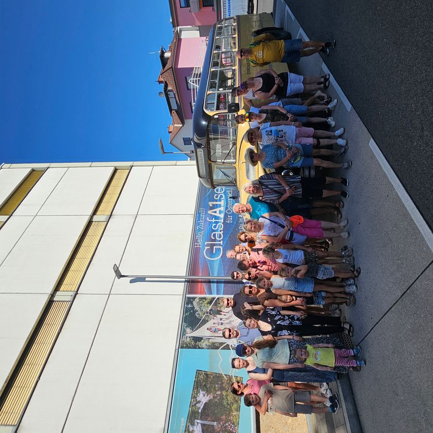Eine Gruppe von Menschen steht vor einem Bus mit einer großen Werbung an der Seite.