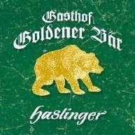 Ein grüner Hintergrund mit einem goldenen Bären-Logo. Über dem Bären stehen die Worte 'Goldener Bar' in Weiß. Unter dem Bären steht das Wort 'Haslinger' in Weiß.