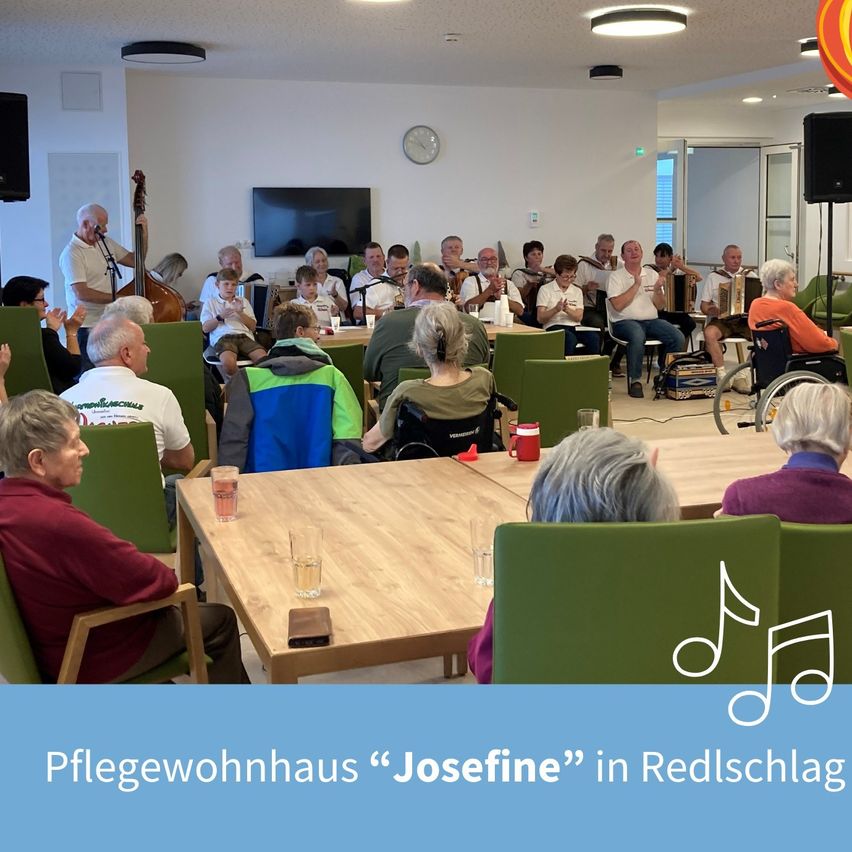 Eine Gruppe älterer Menschen in einem Raum mit Musikinstrumenten. Sie sitzen auf grünen Stühlen, einige stehen. Ein Musiknoten ist unten rechts angezeigt.