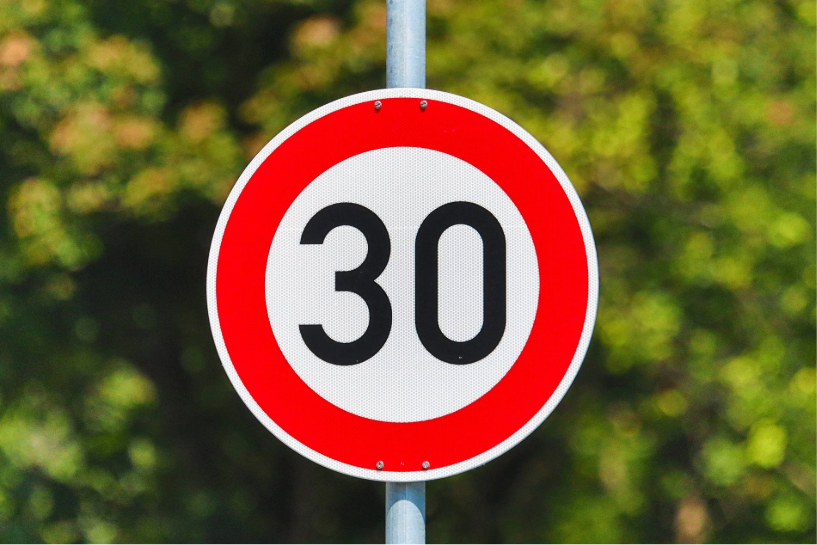 A circular traffic sign with a red border and white center displaying the number 30 in black.