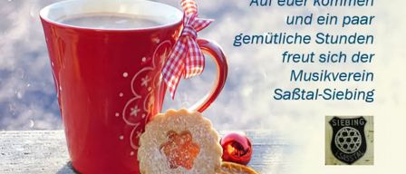 A red coffee mug with a ribbon on a table with cookies and a red ball. A quote in German.