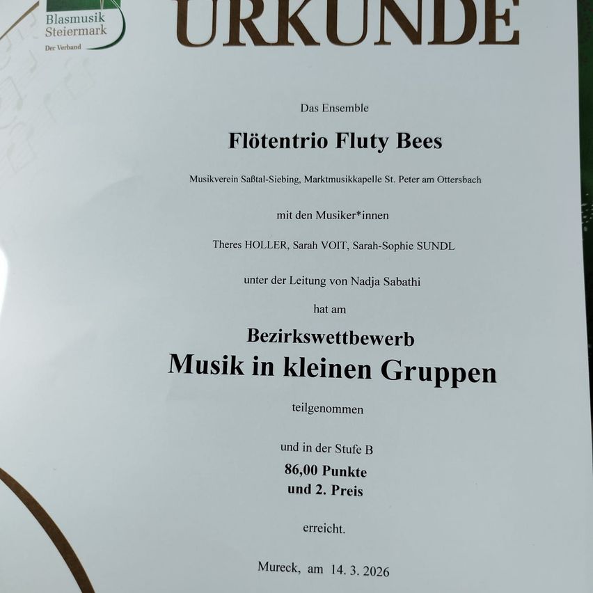 Dokument zeigt ein Musikwettbewerbszertifikat für 'FlotenTrio Fluty Bees'. Das Ensemble nahm am Bezirkswettbewerb 'Musik in kleinen Gruppen' teil, erreichte 86,00 Punkte und gewann den 2. Preis. Datum: 14.03.2026.