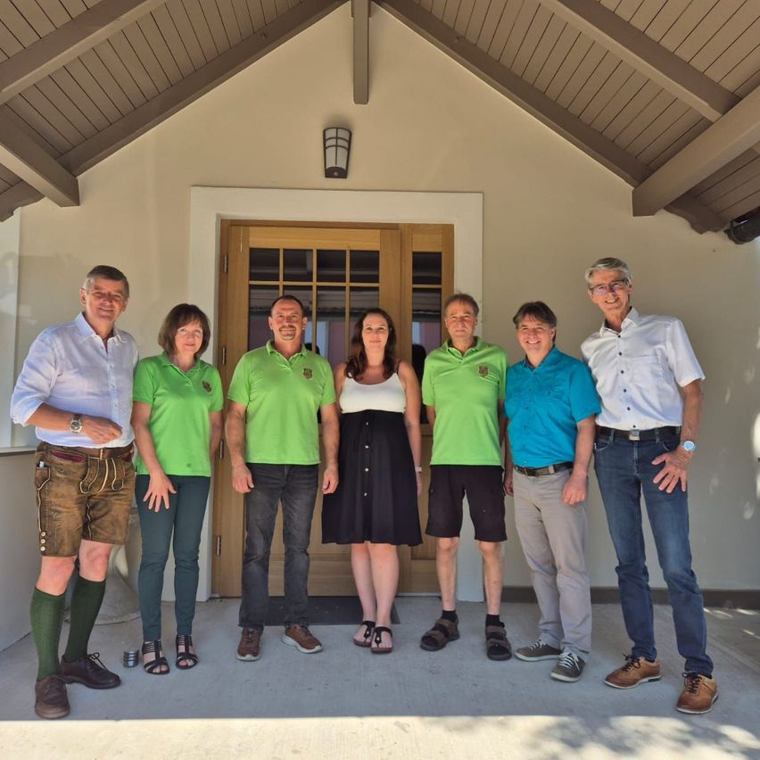A group of people dressed in green and white shirts, posing for a photo in front of a building.