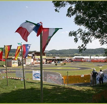 Eine Rennstrecke mit mehreren wehenden Flaggen und Menschen, die neben einem gelben Banner stehen.