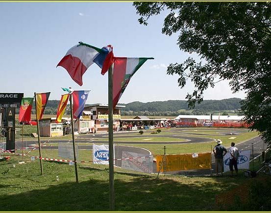 Eine Rennstrecke mit mehreren wehenden Flaggen und Menschen, die neben einem gelben Banner stehen.