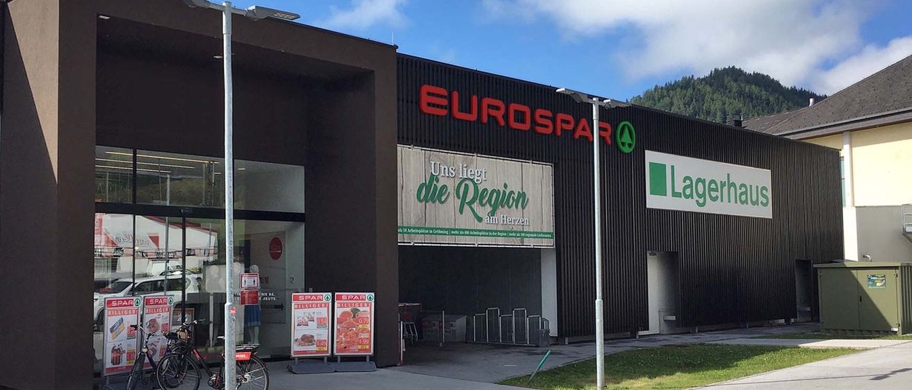 Das Äußere eines EUROSPAR-Geschäfts mit einem Banner, das 'Uns liegt die Region am Herzen' besagt. Ein Fahrrad ist links geparkt.