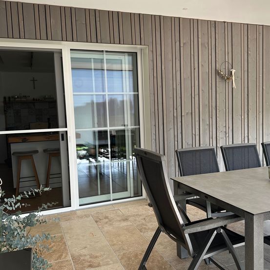 Bild enthält, Indoors, Interior Design, Door, Wood Panels, Chair, Lamp, Sliding Door, Cup, Table