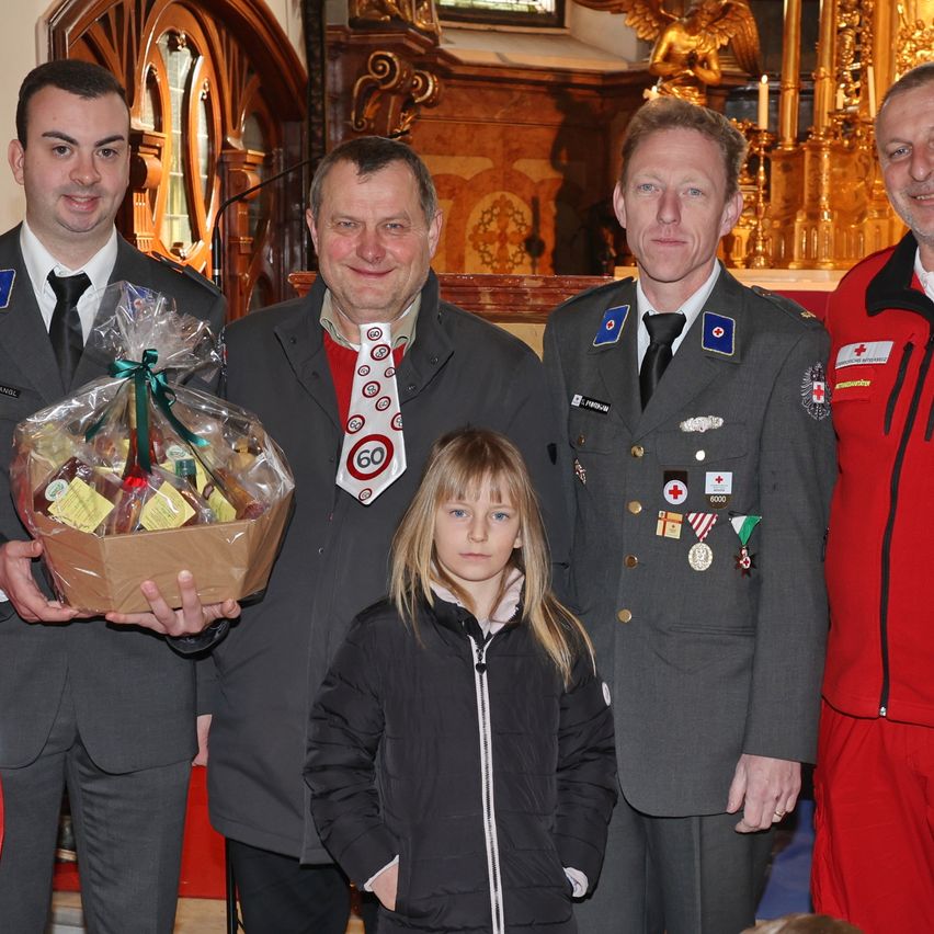 Fünf Erwachsene und ein junges Mädchen stehen lächelnd in einer Kirche. Drei Männer tragen Uniformen, einer mit einer Nummer 60 Krawatte. Das Mädchen hat blonde Haare.