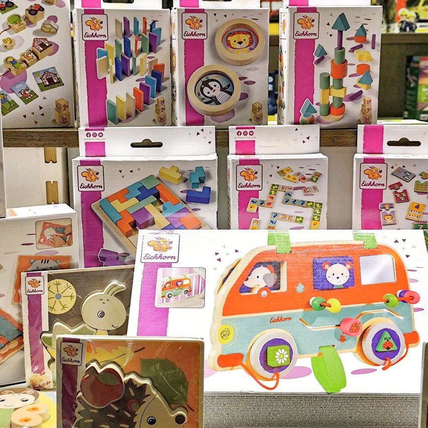 Eine Sammlung von Eichhorn-Spielzeug auf einem Regal, einschließlich eines bunten Holzbusses, Bauklötzen und anderen Spielzeugen.