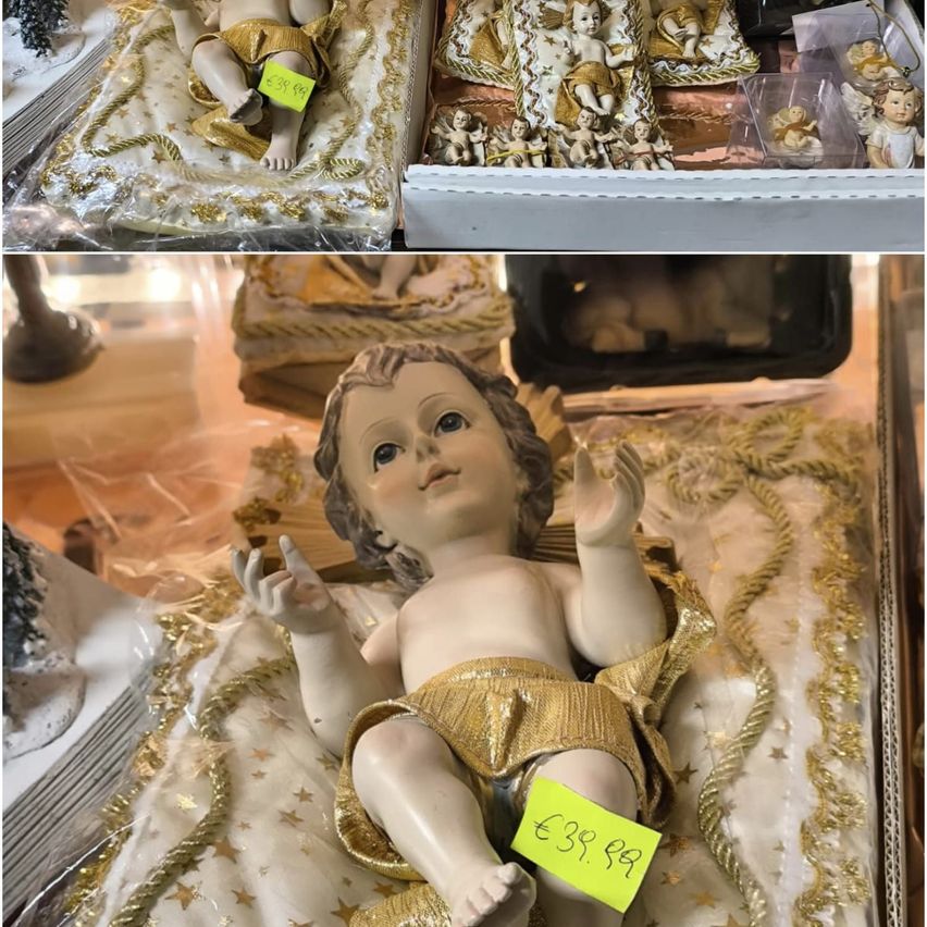 Zwei Figuren in Gold gekleidet, eine liegend und eine sitzend, mit einem Preisschild von 39,99 Euro. Sie sind auf einem weiß-goldenen Tuch mit Sternen ausgestellt. Darüber sind weitere Figuren in Gold und Weiß in einer Box angeordnet.