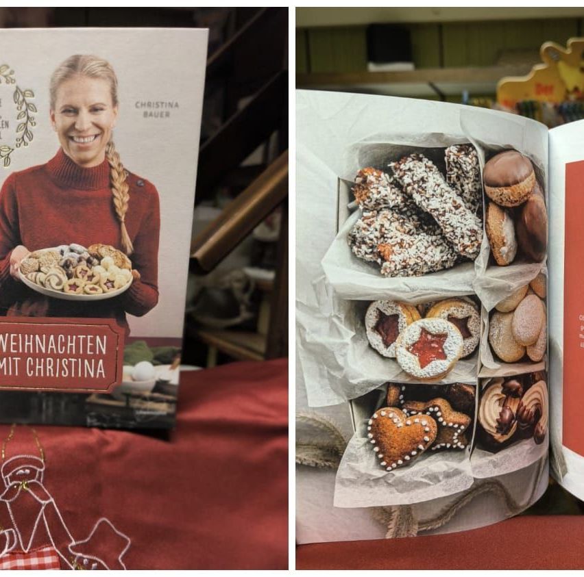 Das Bild zeigt einen Buchumschlag und eine Schachtel mit Weihnachtsplätzchen. Das Buch zeigt eine lächelnde Frau, die einen Teller mit Plätzchen hält. Die Schachtel enthält verschiedene Kekse, darunter herzförmige und sternförmige.