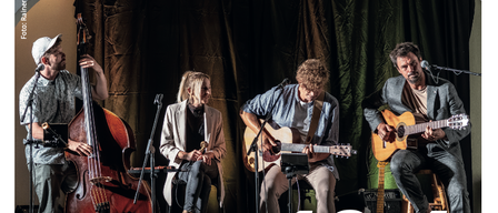 Eine Band mit vier Musikern spielt auf der Bühne mit ihren Instrumenten. Der Plakattext lautet 18.4 und der Bandname Quetschwork Family.