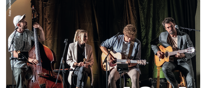 Eine Band mit vier Musikern spielt auf der Bühne mit ihren Instrumenten. Der Plakattext lautet 18.4 und der Bandname Quetschwork Family.