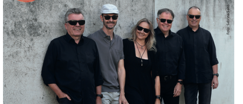 Ein Werbebild für eine Veranstaltung mit einer Gruppe von fünf Personen in schwarzer Kleidung. Das Datum und die Uhrzeit der Veranstaltung sind prominent angezeigt.