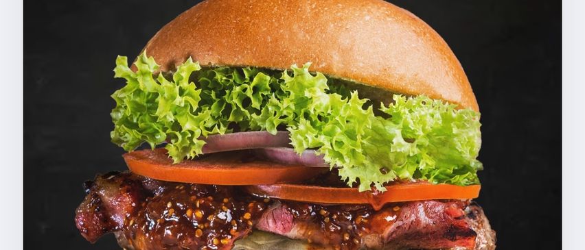 Ein Plakat für den Amerikanischen Tag am 30.01.2026, das einen Burger mit Salat, Tomate und Sauce auf dunklem Hintergrund zeigt.