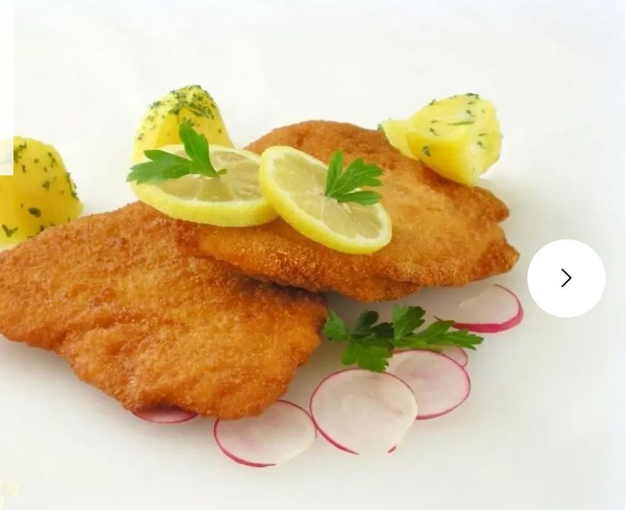 Zwei panierte Hähnchenschnitzel mit Zitronenscheiben und Petersiliengarnitur, begleitet von Kartoffelpüree und Radieschen auf einem weißen Teller.