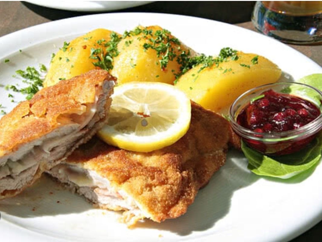 A plate of fried chicken, mashed potatoes, and cranberry sauce with a lemon slice. The chicken is crispy, and the potatoes are garnished with parsley.