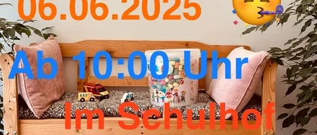 Eine Holzbank mit Kissen steht im Schulhof der VS Arnfels. Ein Eimer mit Süßigkeiten und Spielzeug ist auf der Bank. Die Wand dahinter hat ein Flohmarkt-Poster und ein lächelndes Emoji. Das Datum ist 06.06.2025.