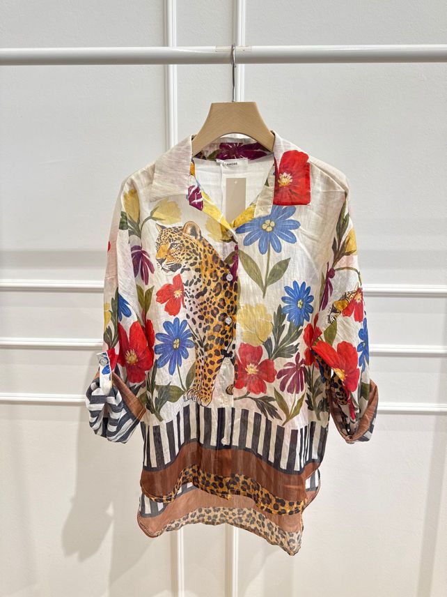A vibrant floral and leopard print blouse with a mix of red, blue, and yellow flowers, hanging on a hanger against a white background.
