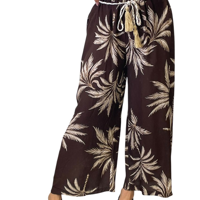 A person wearing wide-legged pants with a palm tree print, featuring a white drawstring at the waist.