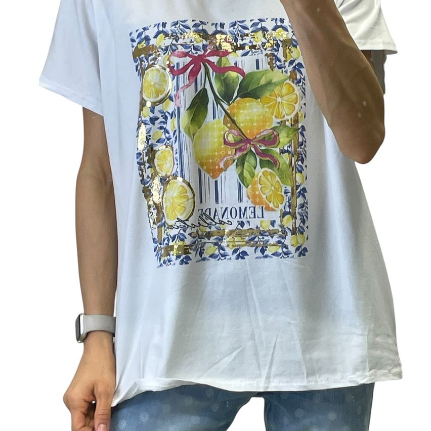 A person wearing a white t-shirt with a lemon print and blue floral design. The shirt has a gold-colored border and text in white.