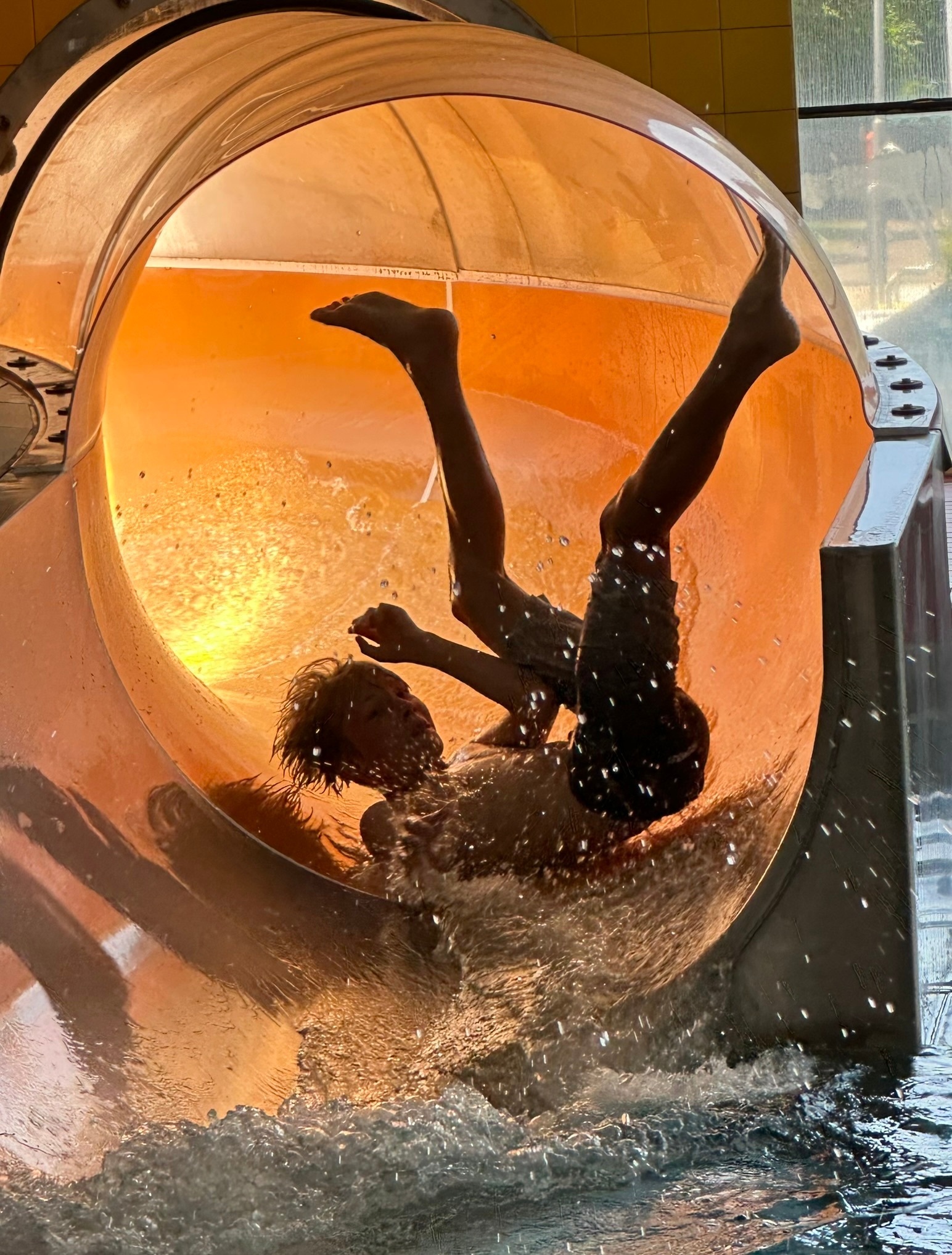 Kind rutscht mit vollem Körpereinsatz die Rutsche im Freibad hinunter