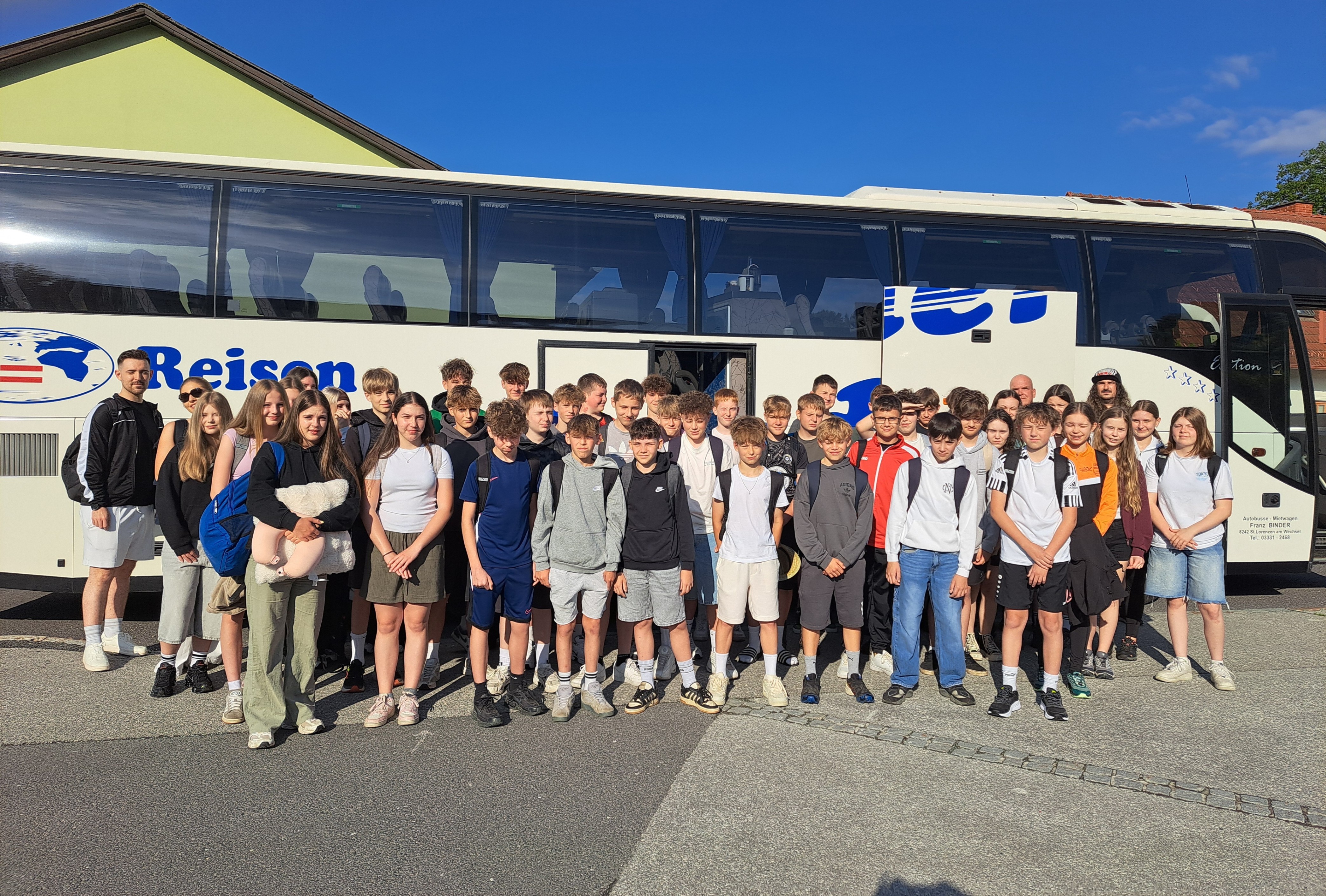 Jugendliche und Erwachsene stehen vor einem Reisebus der Firma Binder in St. Lorenzen am Wechsel