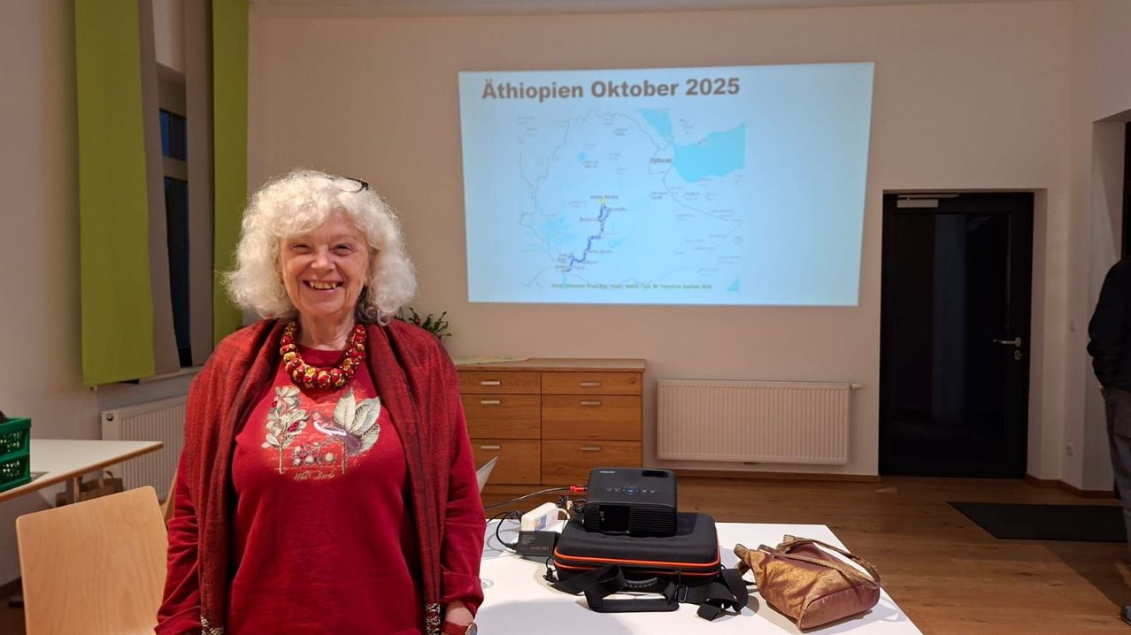 Eine Frau in einem roten Pullover und einer Halskette steht vor einer Projektionsleinwand mit einer Karte Äthiopiens und dem Datum Oktober 2025.