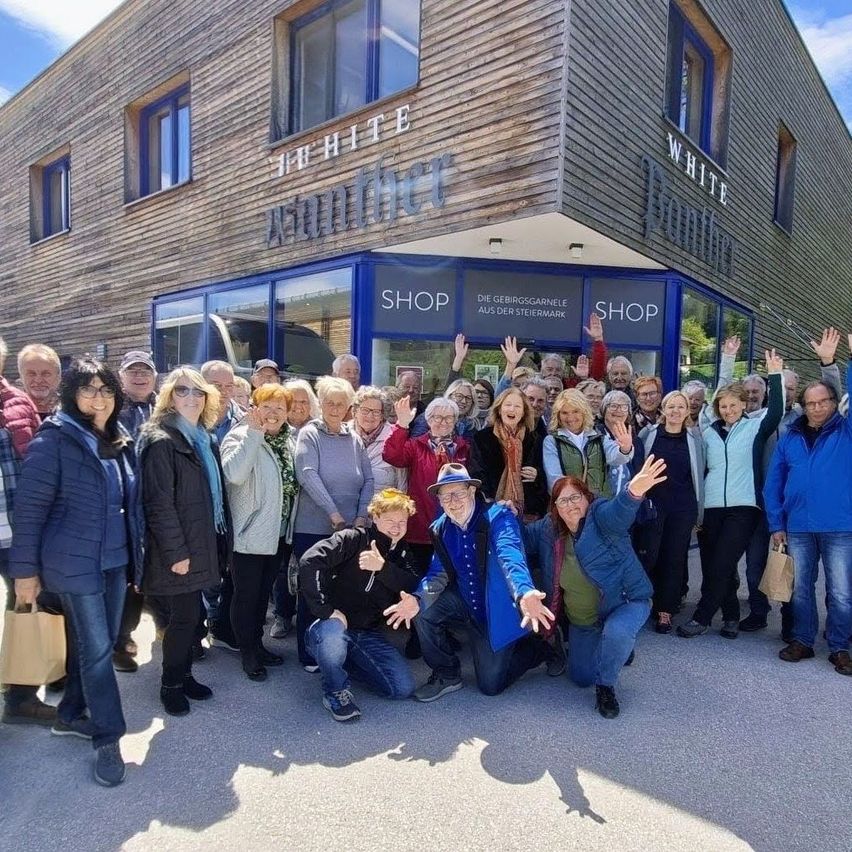 Eine Gruppe von Menschen steht vor einem Geschäft namens White Mountain, alle lächeln und posieren für ein Foto.