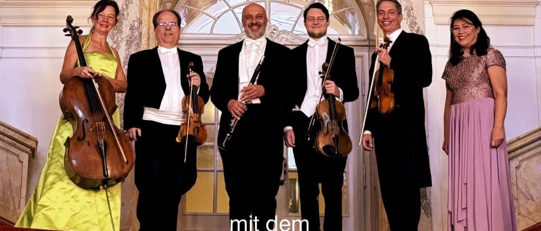 Plakat für ein Neujahrskonzert in Strass mit dem Girardi Ensemble Graz. Fünf Musiker stehen vor einem Gebäude und halten ihre Instrumente. Das Plakat enthält Details zum Event, Datum und Ticketpreisen.