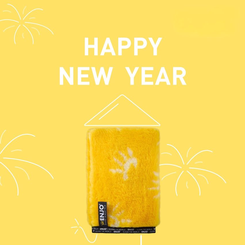 Ein gelber Schwamm mit den Worten Happy New Year oben. Unten steht 'EJO' und 'CLEAN THE WORLD'. Im Hintergrund sind Feuerwerke zu sehen.