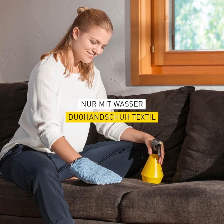 Eine Frau mit Handschuhen sitzt auf einer Couch und reinigt sie mit einer gelben Sprühflasche. Die Couch ist braun, und die Frau lächelt. Es gibt einen Textüberlagerung, der 'Nur mit Wasser' und 'DuoHandschuh Textil' lautet.