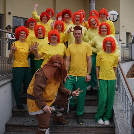 Eine Gruppe von Menschen in gelben und grünen Kostümen, wahrscheinlich für eine Kostümparty, posiert auf den Stufen.