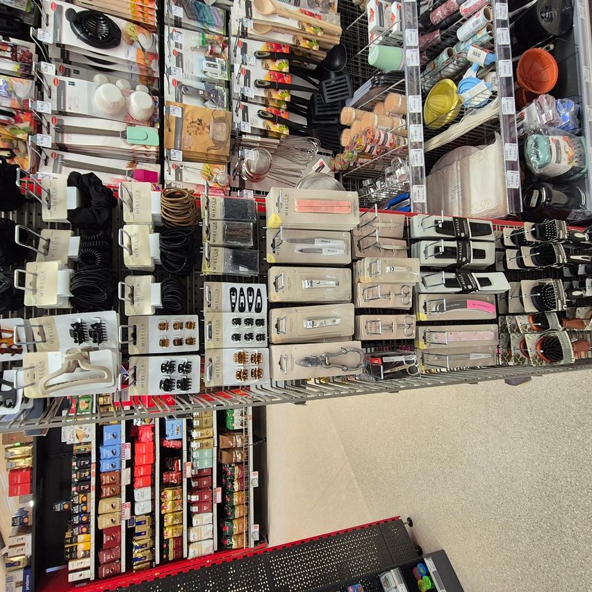 Ein Gang gefüllt mit verschiedenen Haaraccessoires und Werkzeugen, einschließlich Haarklemmen, Kämmen und Haargummis. Regale mit verschiedenen Produkten, einschließlich Küchenutensilien und Lebensmitteln.