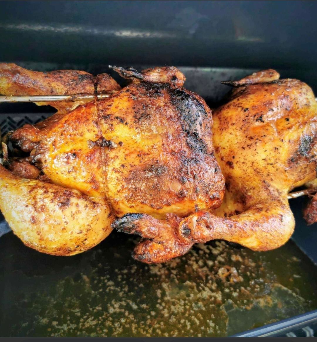 Two fully cooked chickens are being grilled on a grill. The chickens are well-cooked and have a golden-brown color.