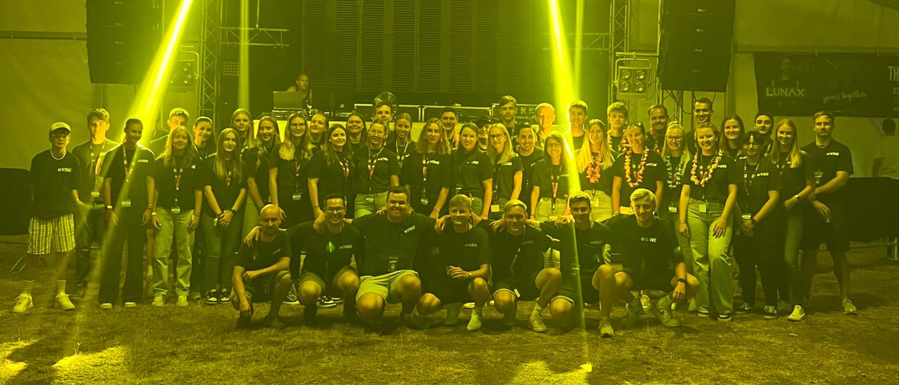 Eine Gruppe von Menschen in gleichen Shirts posiert für ein Foto in einem Zelt mit gelbem Licht.