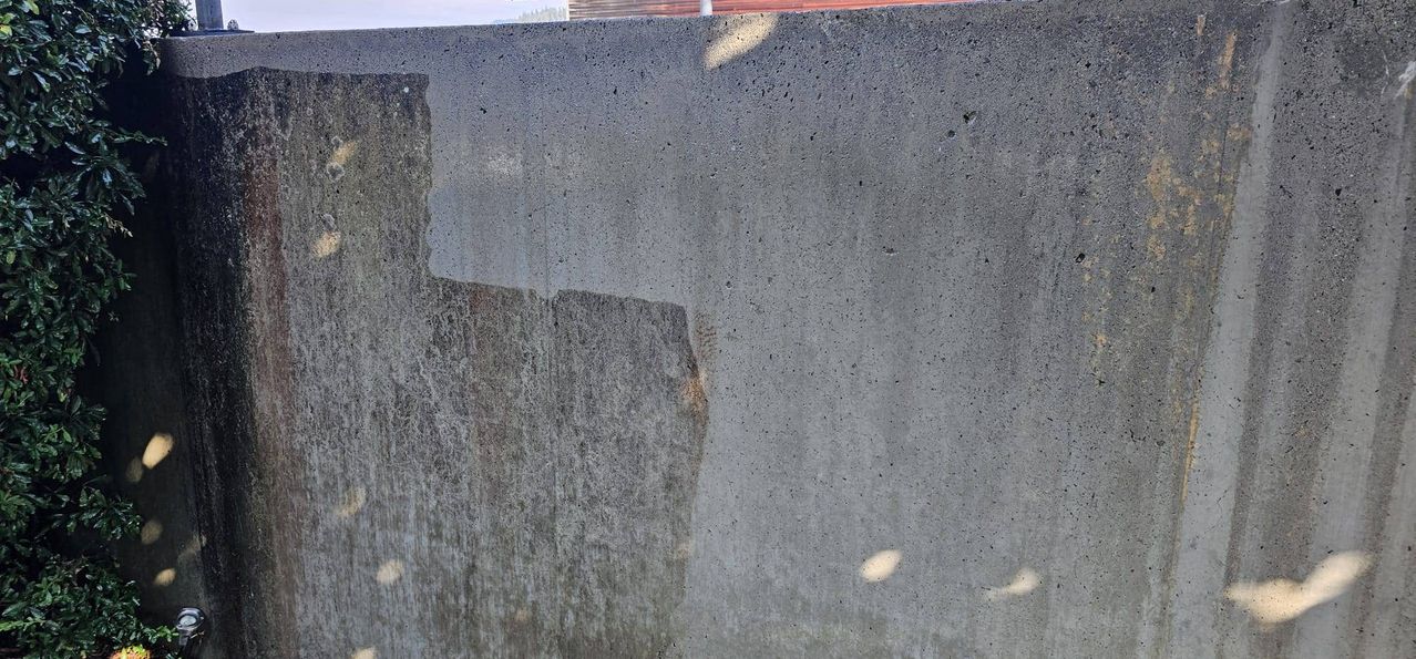 Eine Nahaufnahme einer grauen Betonwand mit sichtbarer Textur und kleinen Löchern, möglicherweise Anzeichen von Abnutzung.