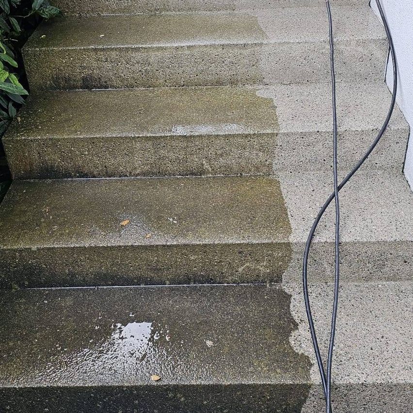 Ein Nahaufnahme von Betonstufen, die mit einem Hochdruckreiniger gereinigt werden, wobei Wasser die Stufen hinunterläuft.