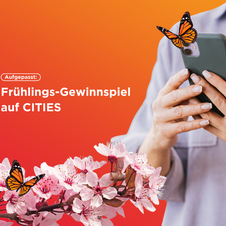 Frühlings-Gewinnspiel auf CITIES mit einer Person, die ein Handy mit einem Schmetterling darauf hält. Es gibt einen Strauß rosa Blumen. Der Text lautet "Frühlings-Gewinnspiel auf CITIES."
