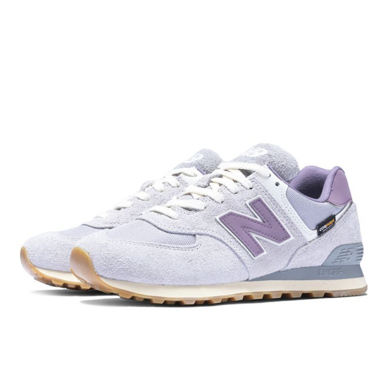 Ein Paar weiße und lila New Balance 574 Sneakers mit brauner Sohle und weißen Schnürsenkeln vor weißem Hintergrund.