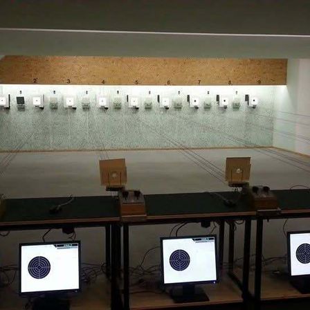 Ein Schießstand mit nummerierten Zielen und Monitoren. Jeder Monitor zeigt ein Ziel mit einem Bullauge.