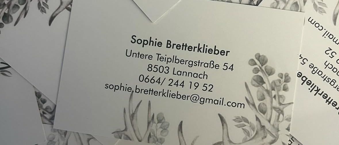 Ein Stapel weißer Visitenkarten mit Blumen- und Geweih-Designs. Die oberste Karte zeigt den Namen Sophie Bretterklieber, Adresse, Telefonnummer und E-Mail.